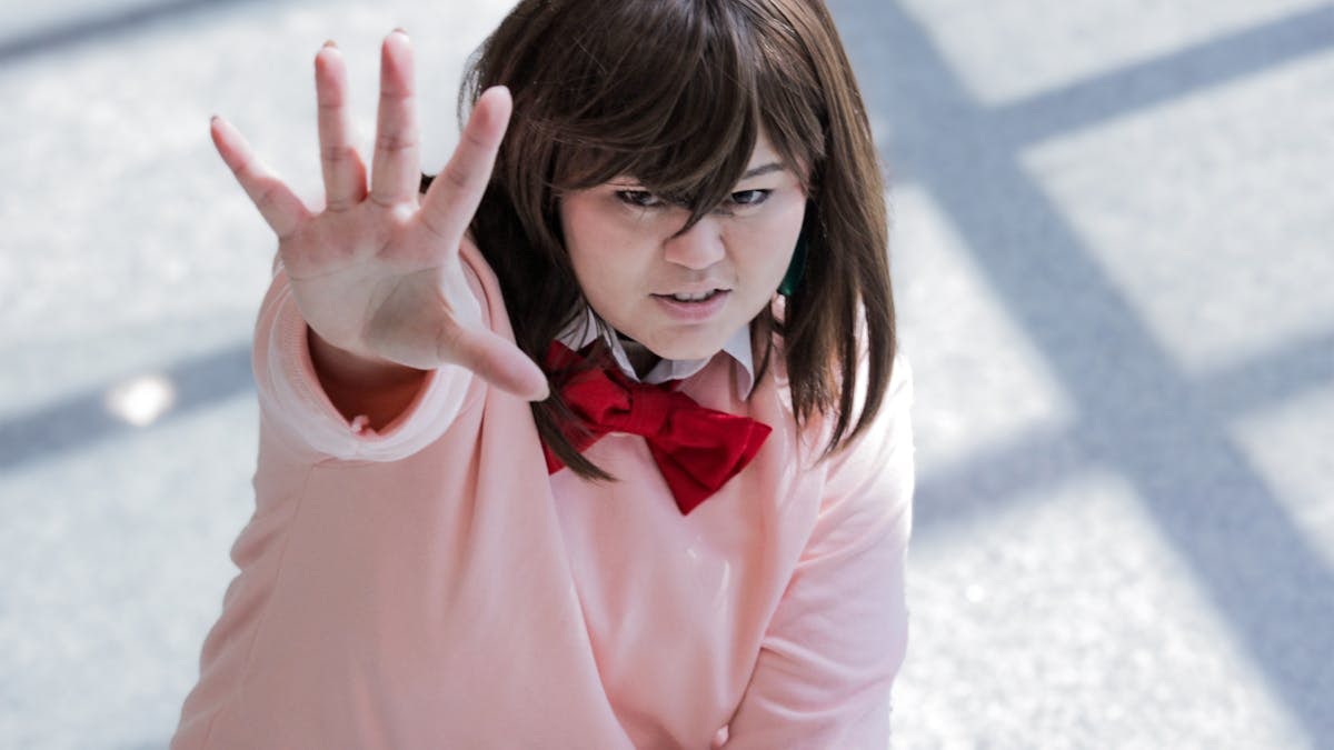 Young adult in anime-inspired cosplay, energetically posing indoors.
