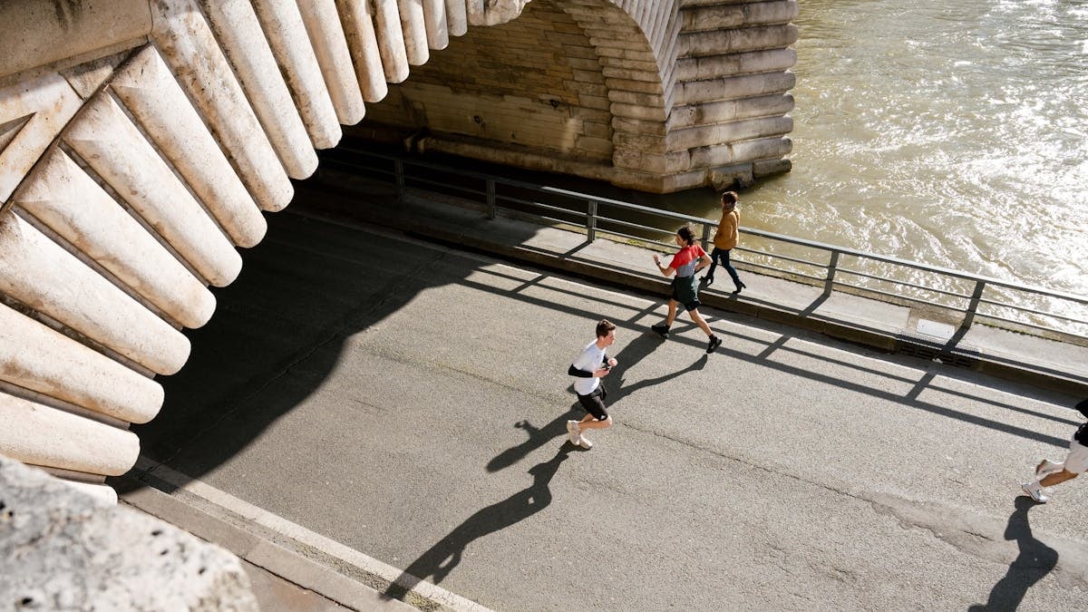 View of joggers running under the Pont de Bir-Hakeim in Paris, France during the day.